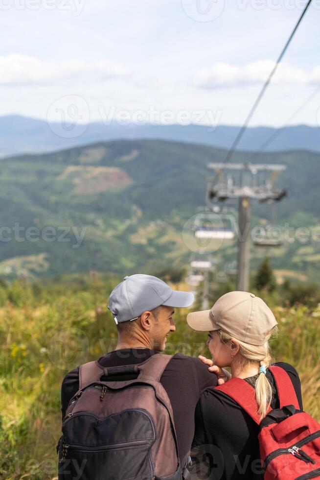 People sit on the ski elevator. View from the back. Summer, green forest. summer family vacation in the mountains. photo