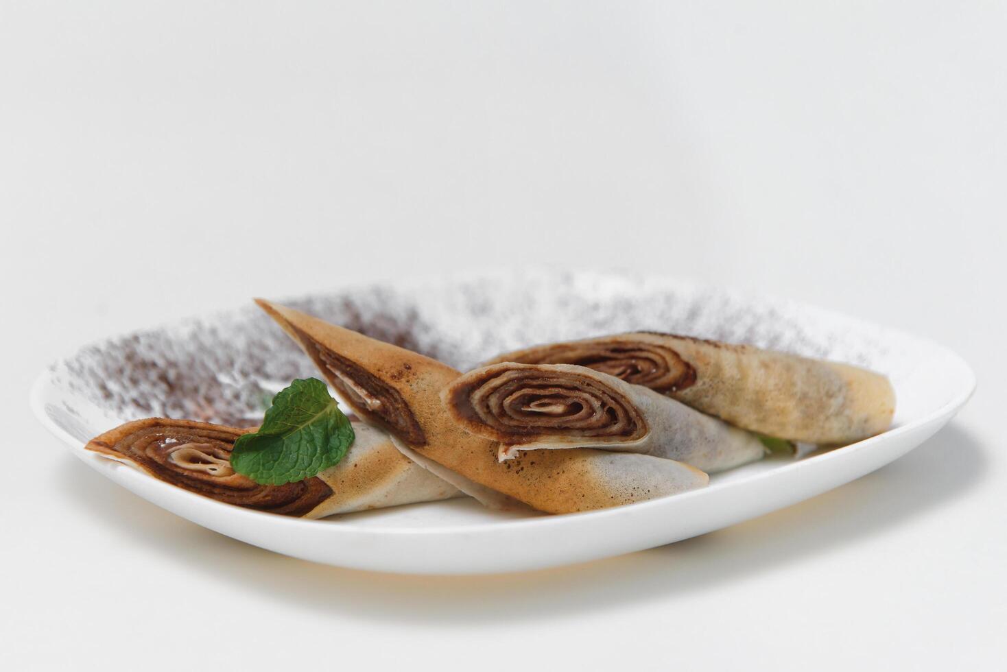 close-up crepe with bananas and chocolate on white plate photo