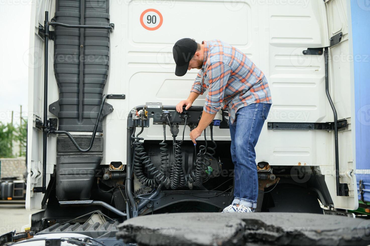 View of a driver connecting the power cables to trailer of a commercial truck. photo