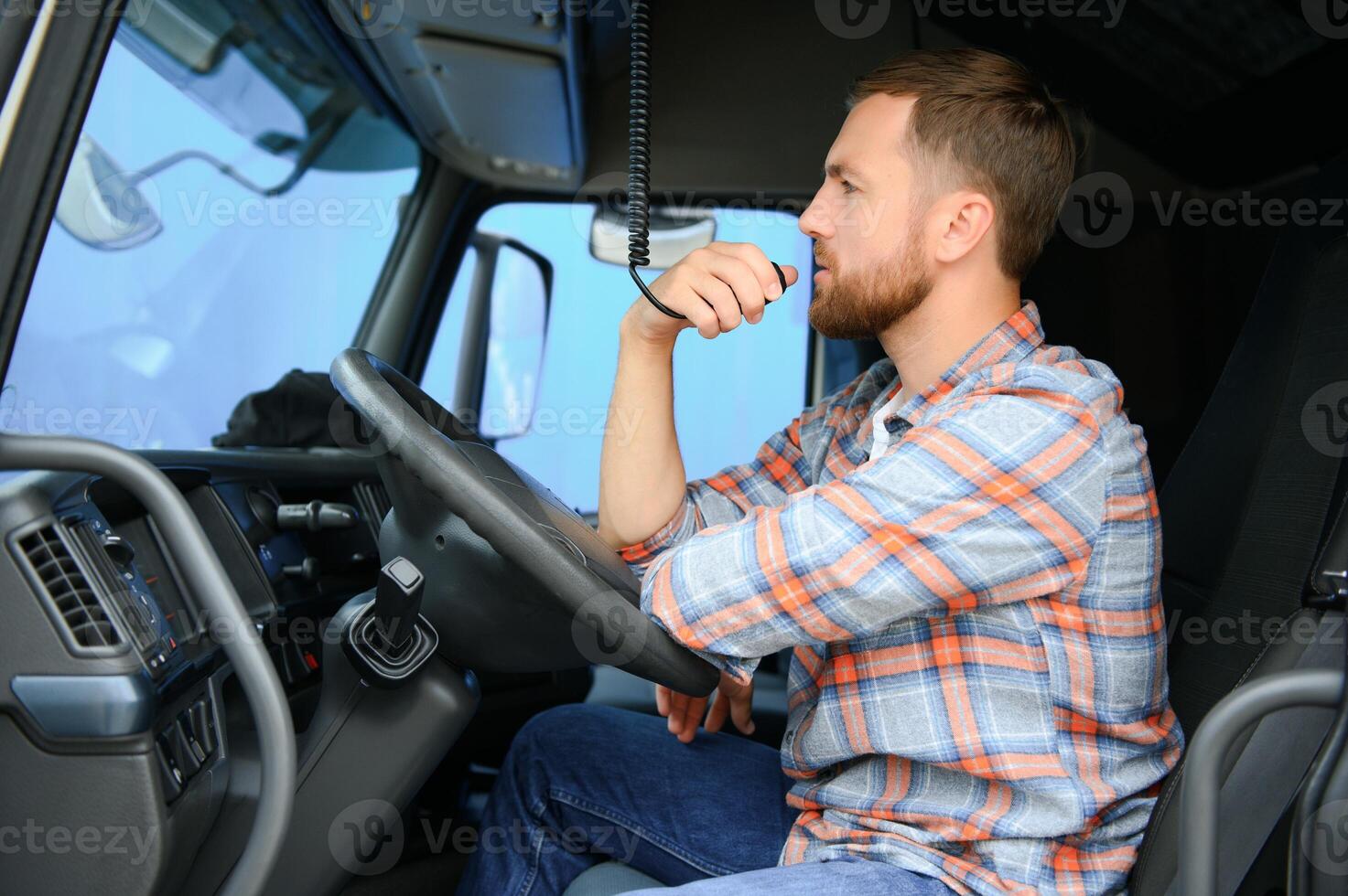 Male truck driver talking by CB radio system in his vehicle photo