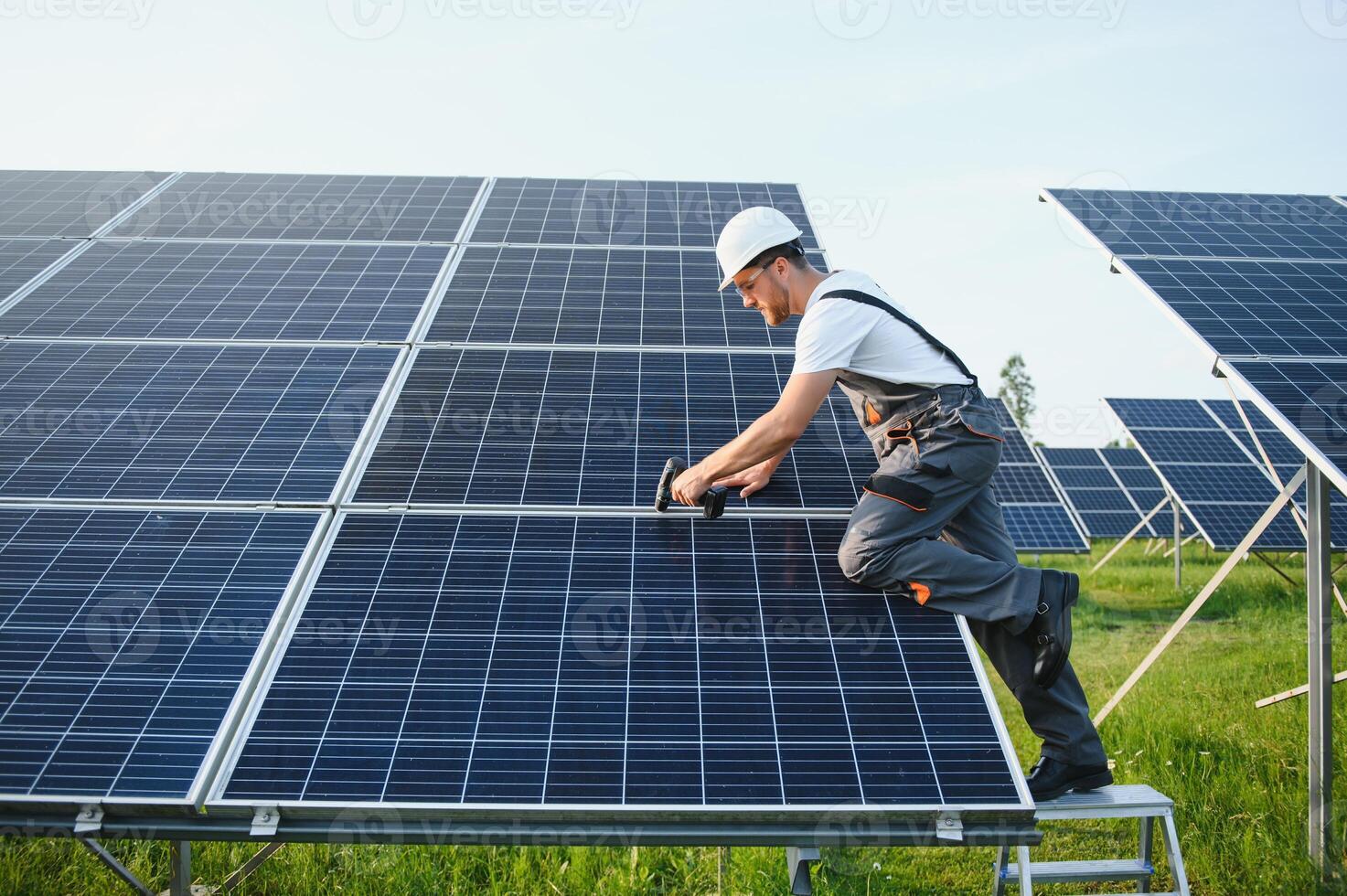 lado ver de masculino trabajador instalando solar módulos y apoyo estructuras de fotovoltaica solar formación. electricista vistiendo la seguridad casco mientras trabajando con solar panel. concepto de Dom energía foto