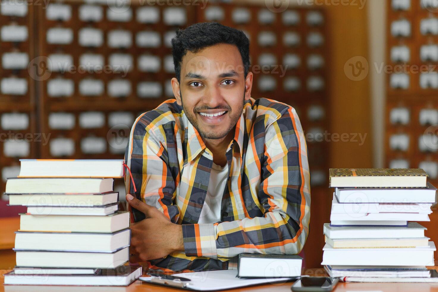 Happy smart indian or arabian guy, mixed race male, university student, in the library photo