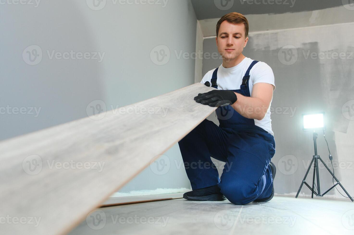 DIY, repair, building and home concept - man lying parquet floor board or laminate flooring photo