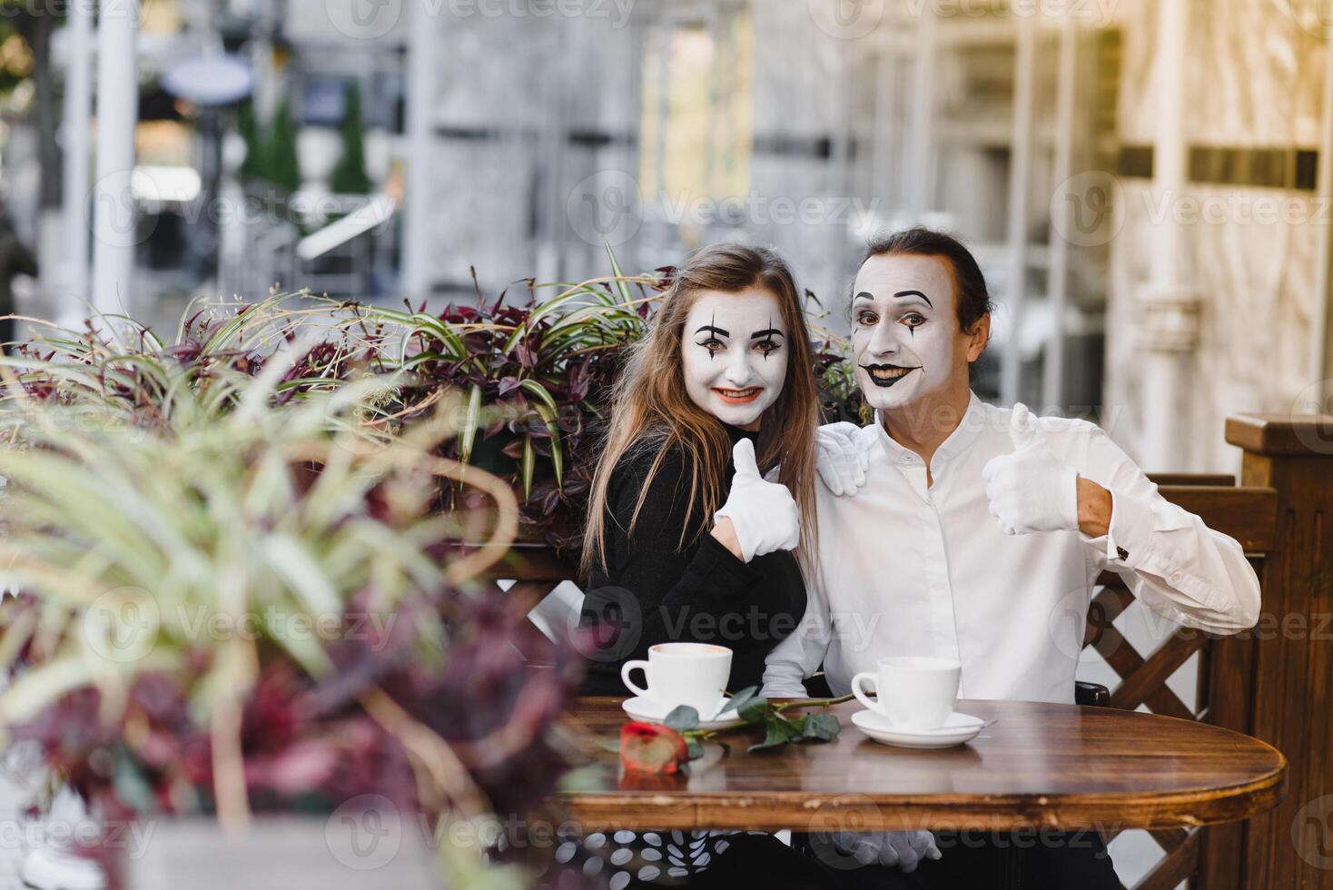 mime guy and girl in cafe drinking coffee. Mime in front of Paris cafe acting like drinking tea or coffee. photo