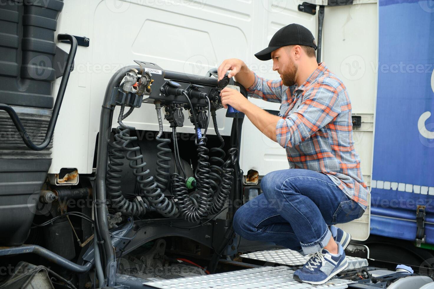 View of a driver connecting the power cables to trailer of a commercial truck. photo