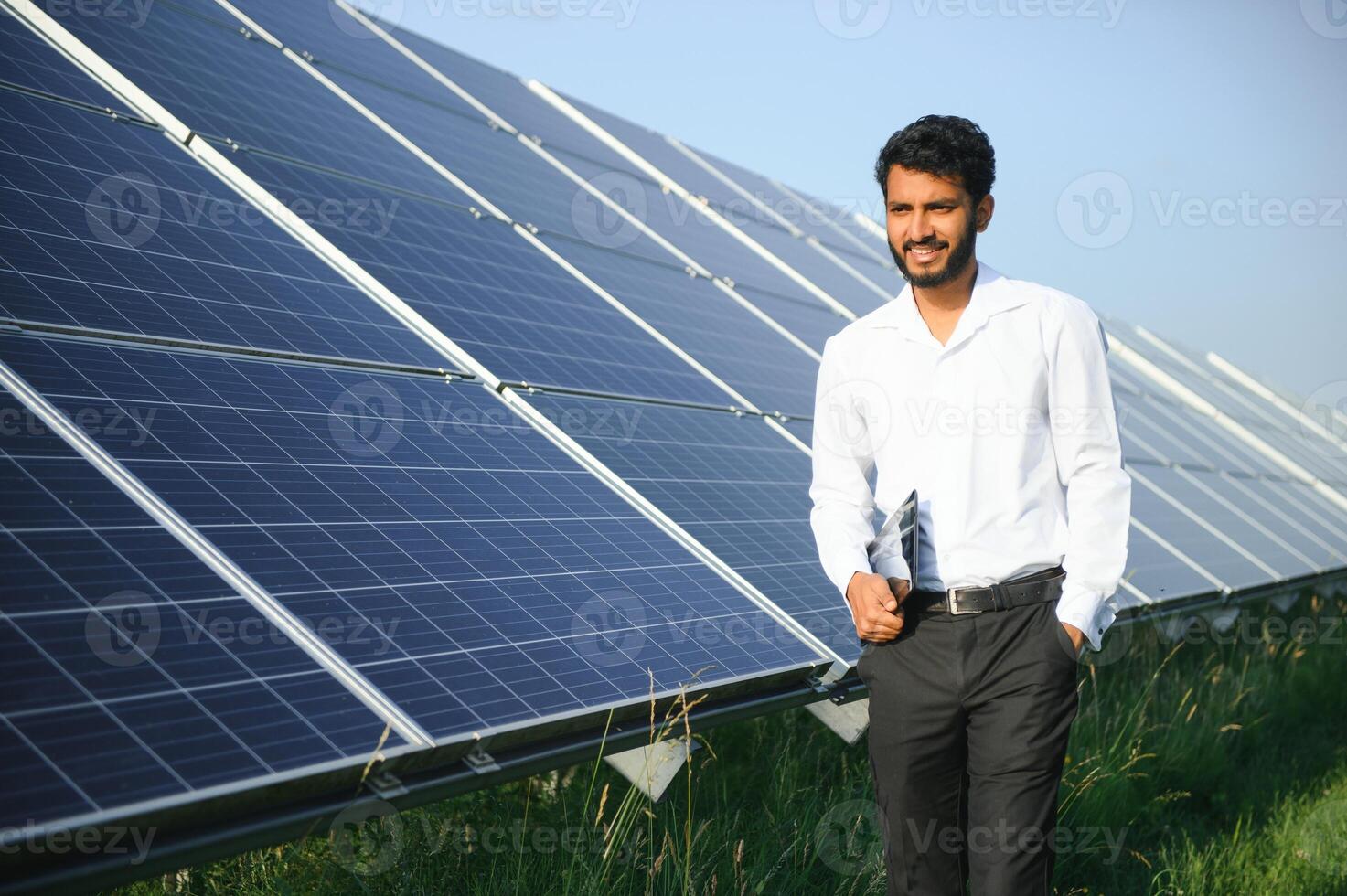 male engineer checks a photovoltaic solar plant and uses a recording tablet. Indian Man in uniform holding tablet. photo