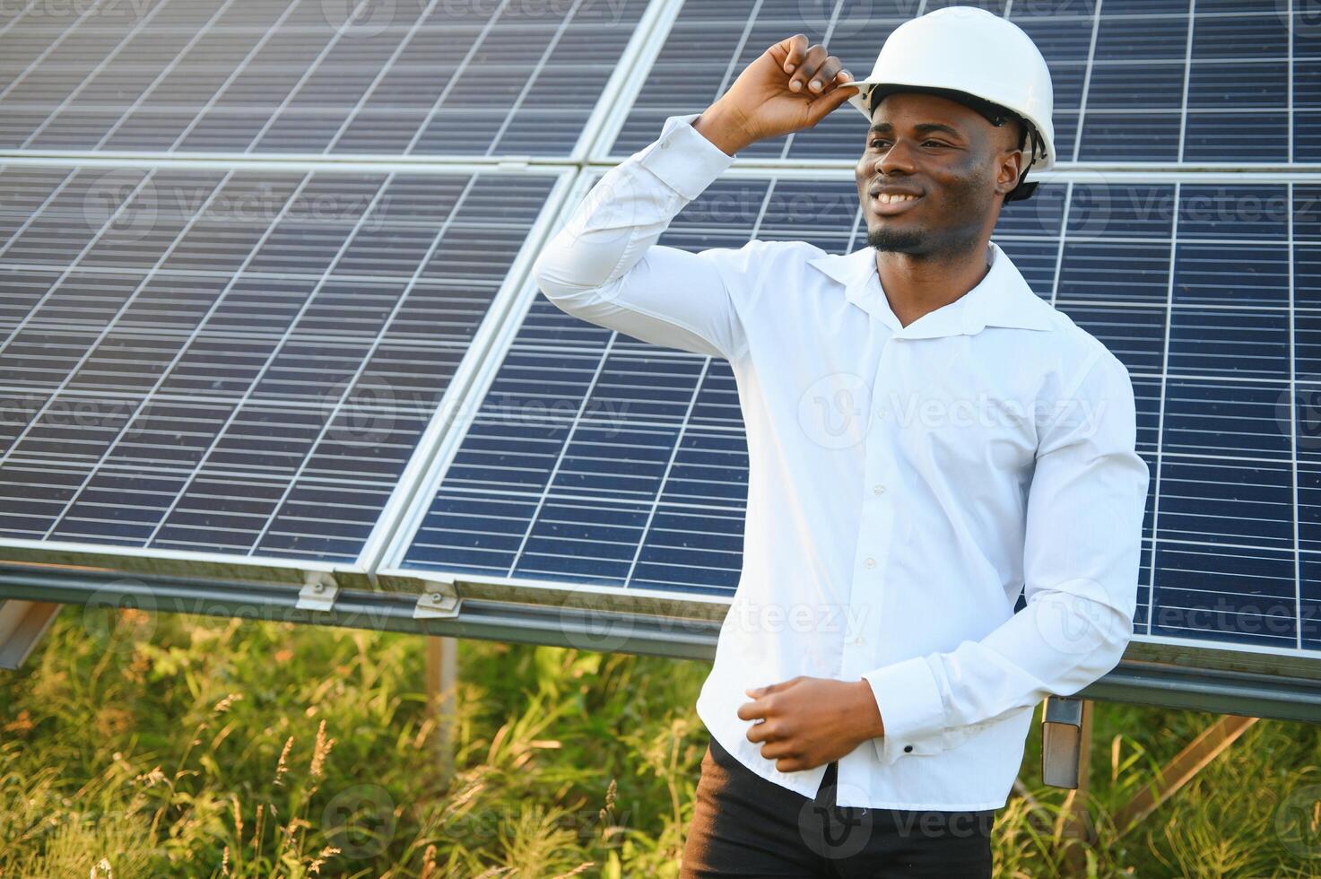 Close up portrait of young handsome African American craftsman a protective helmet. Happy man in overalls posing at camera smiling. Slow motion. photo