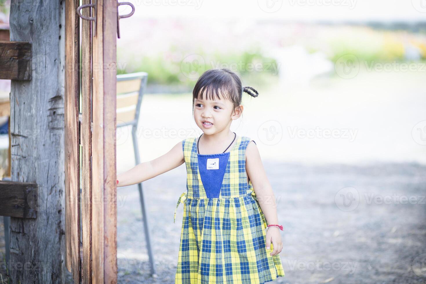 un niña abre el puerta a un flor jardín y da la bienvenida sí misma dentro hermosa naturaleza. foto