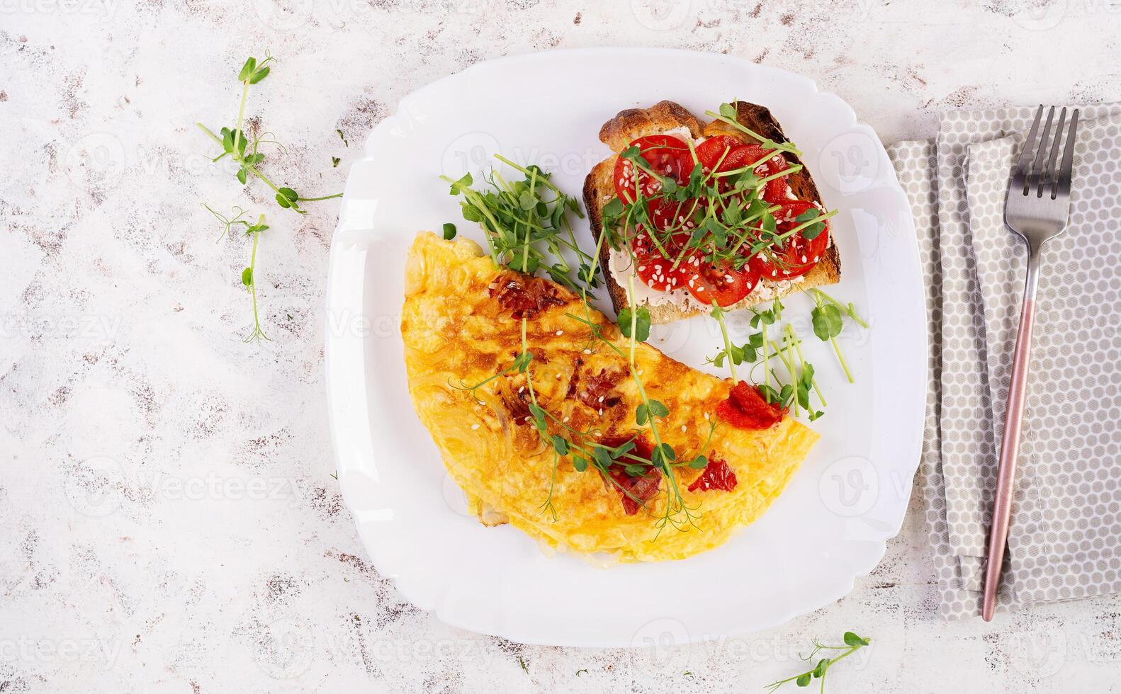 Omelette with cheese and toast with tomatoes on white plate.  Frittata - italian omelet. Top view, flat lay photo
