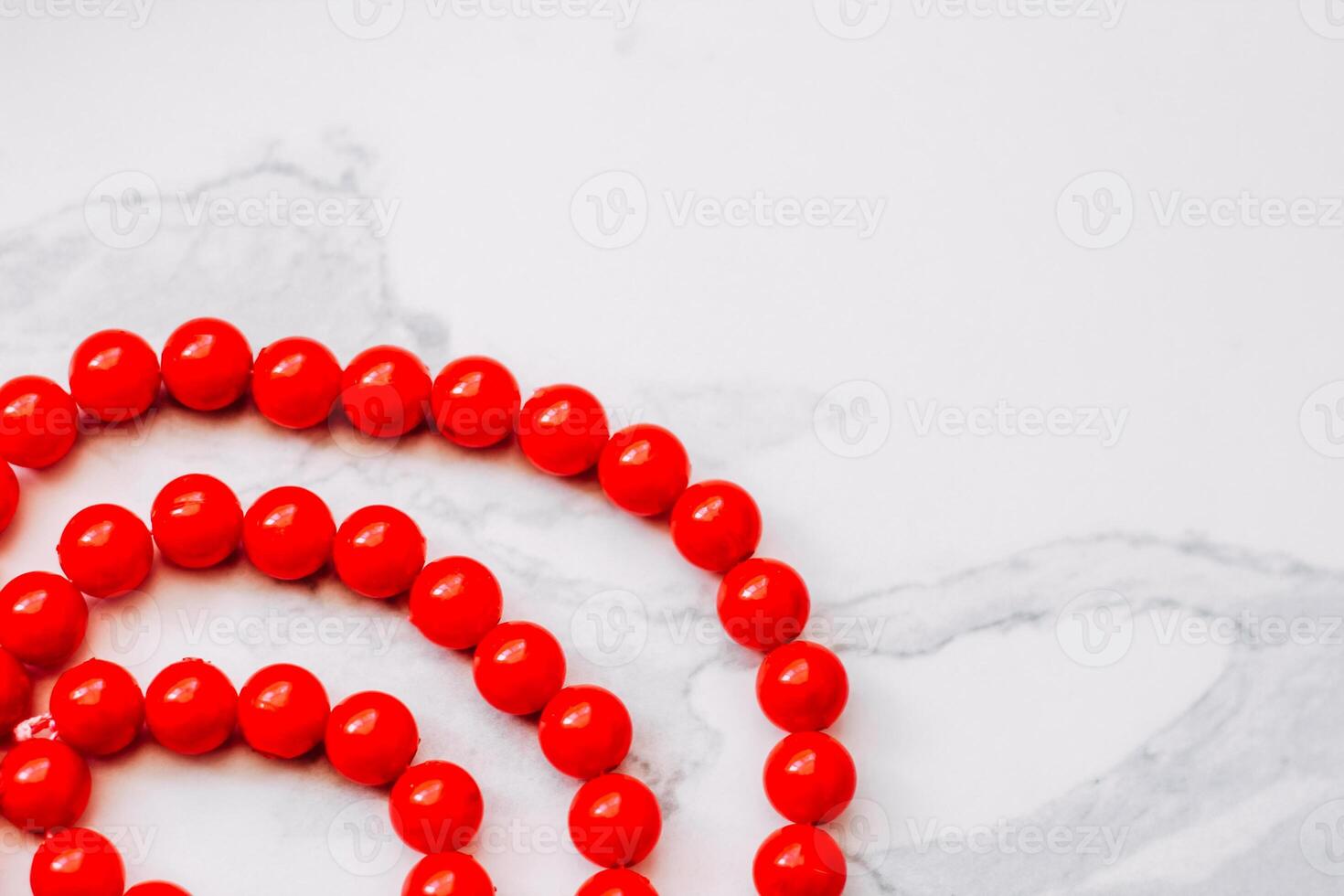 A necklace of red beads on a white aesthetic background. photo