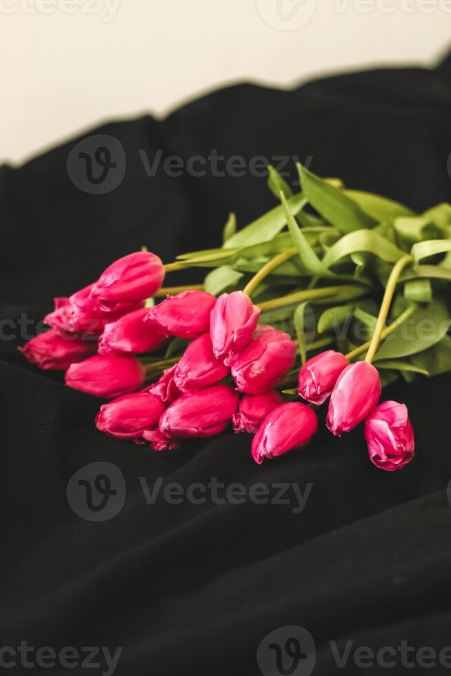 A bouquet of pink flowers sewn on black stylish linen. photo