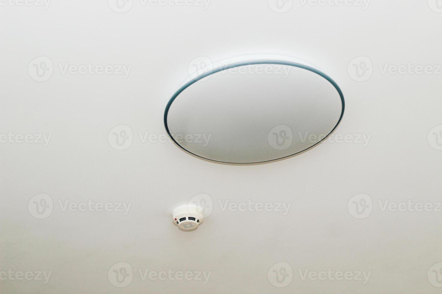 A fire alarm sensor on the ceiling with a chandelier. photo