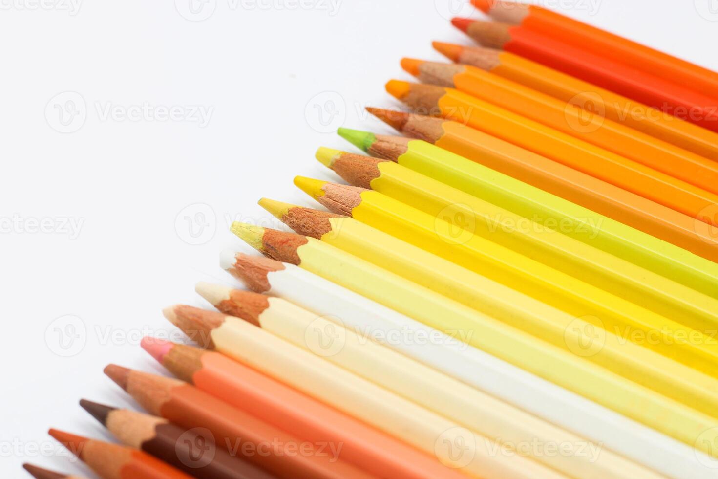 Multi-colored pencils lie on a white table, the red range of colors photo