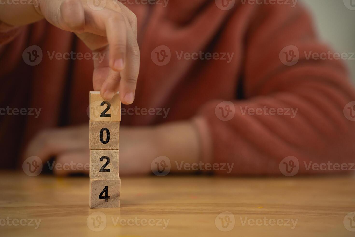 New year 2024 concept. Hand Stacking Wooden Blocks. Achieve goal success. Close-up of woman hand strategy placing wooden blocks with numbers and a bullseye, concept of goal setting. photo