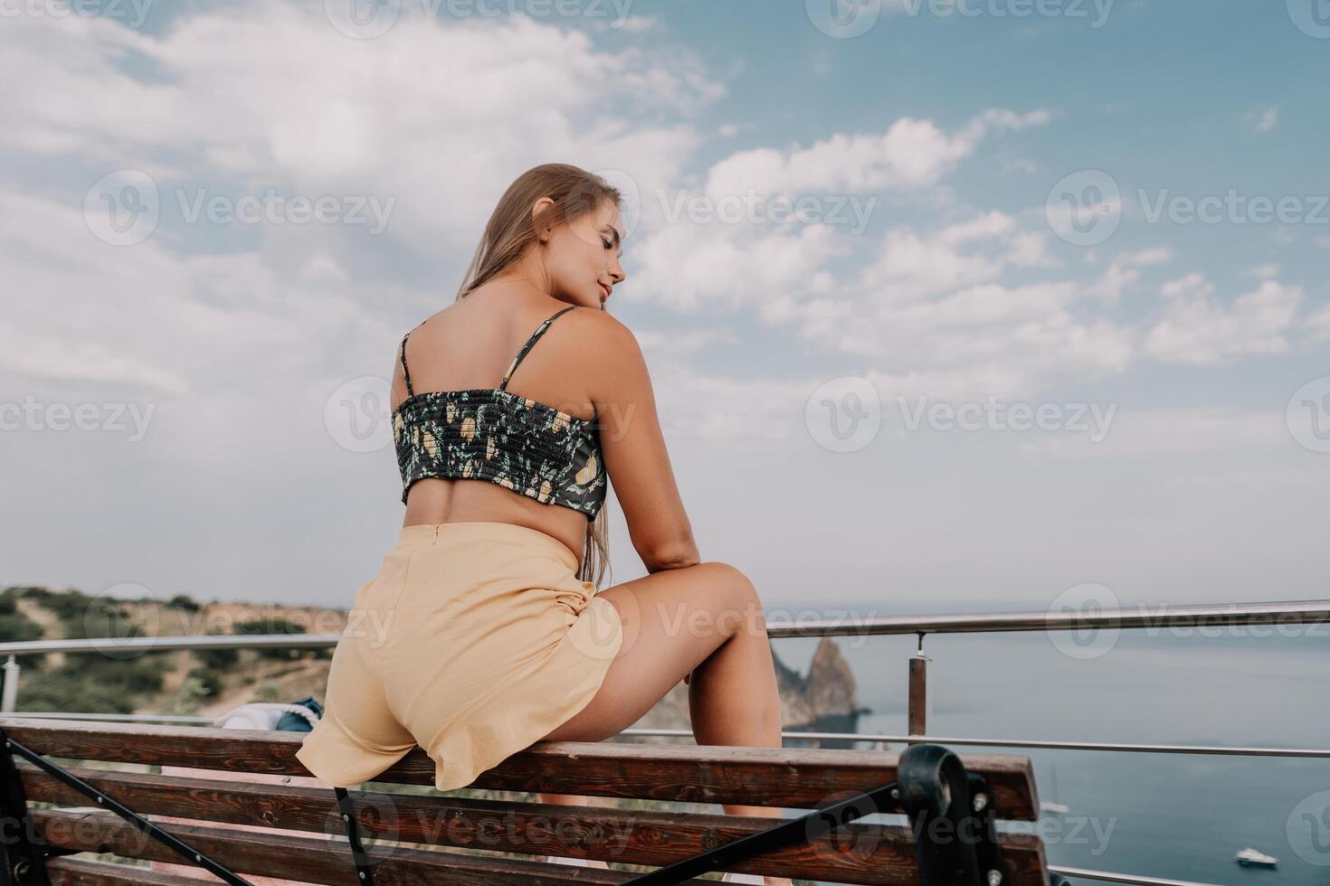 Woman travel sea. Happy tourist enjoy taking picture outdoors for memories. Woman traveler looks at the edge of the cliff on the sea bay of mountains, sharing travel adventure journey photo