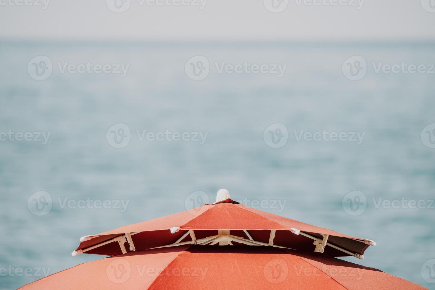 Red Beach Umbrella on the Background of the Blue Sea Ocean. Beach Landscape. Summer travel and holidays concept. photo