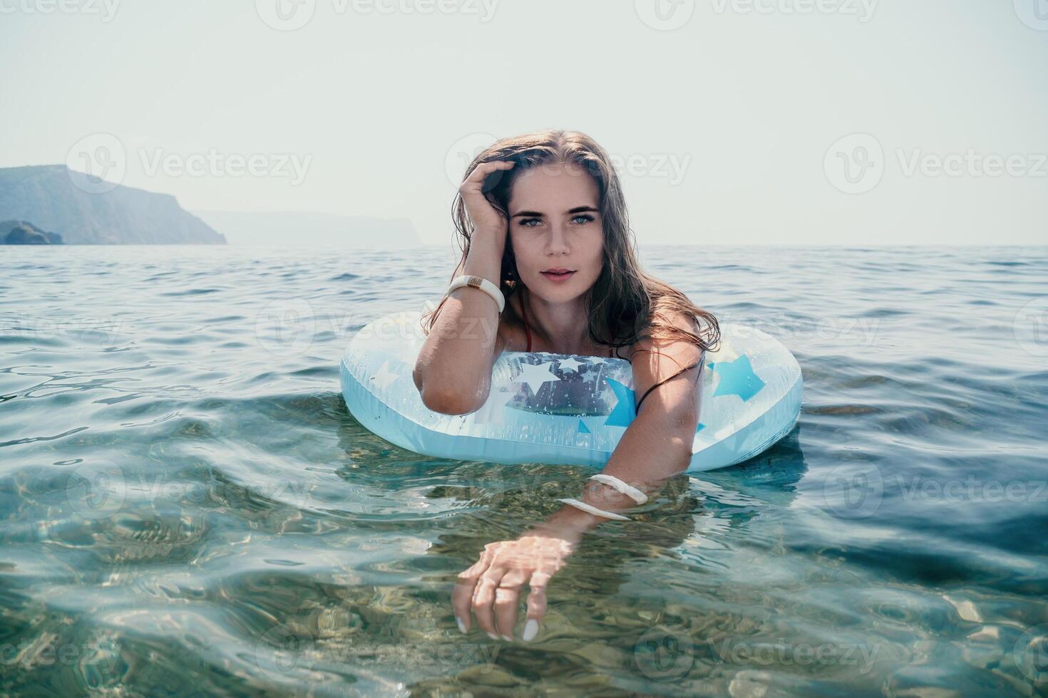 Woman summer sea. Happy woman swimming with inflatable donut on the beach in summer sunny day, surrounded by volcanic mountains. Summer vacation concept. photo