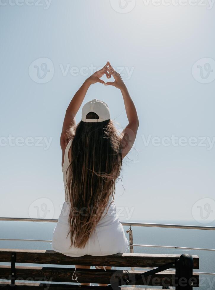 Woman summer travel sea. Happy tourist enjoy taking picture outdoors for memories. Woman traveler posing over sea bay surrounded by volcanic mountains, sharing travel adventure journey photo