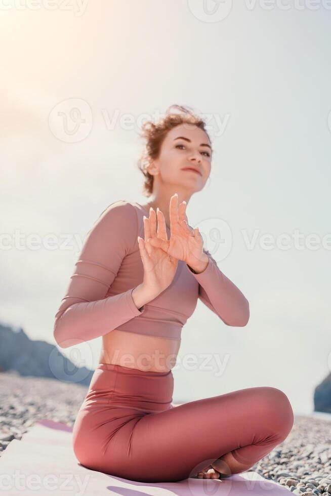 medio Envejecido bien mirando mujer con negro cabello, aptitud instructor en polainas y tapas haciendo extensión y pilates en yoga estera cerca el mar. hembra aptitud yoga rutina concepto. sano estilo de vida foto