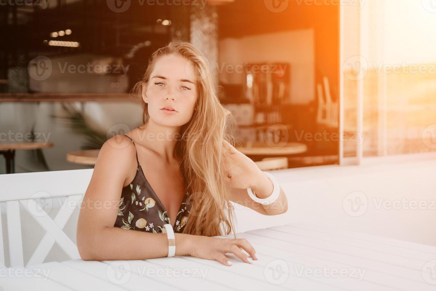 contento mujer retrato en cafetería. boho elegante Moda estilo. al aire libre foto de joven contento mujer con largo cabello, soleado clima al aire libre sentado en moderno cafetería.