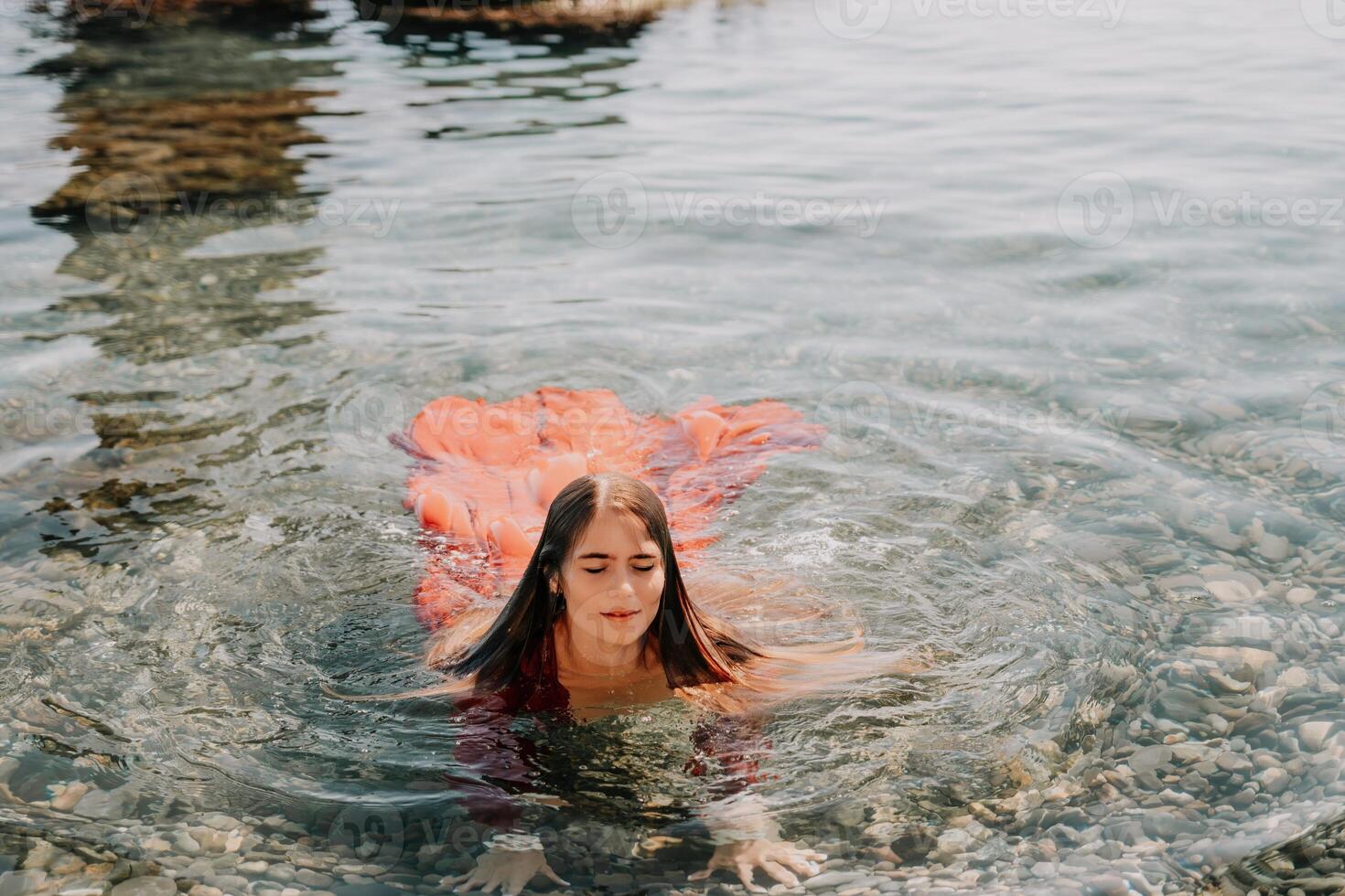 Woman travel sea. Happy tourist in red dress enjoy taking picture outdoors for memories. Woman traveler posing in sea beach, surrounded by volcanic mountains, sharing travel adventure journey photo