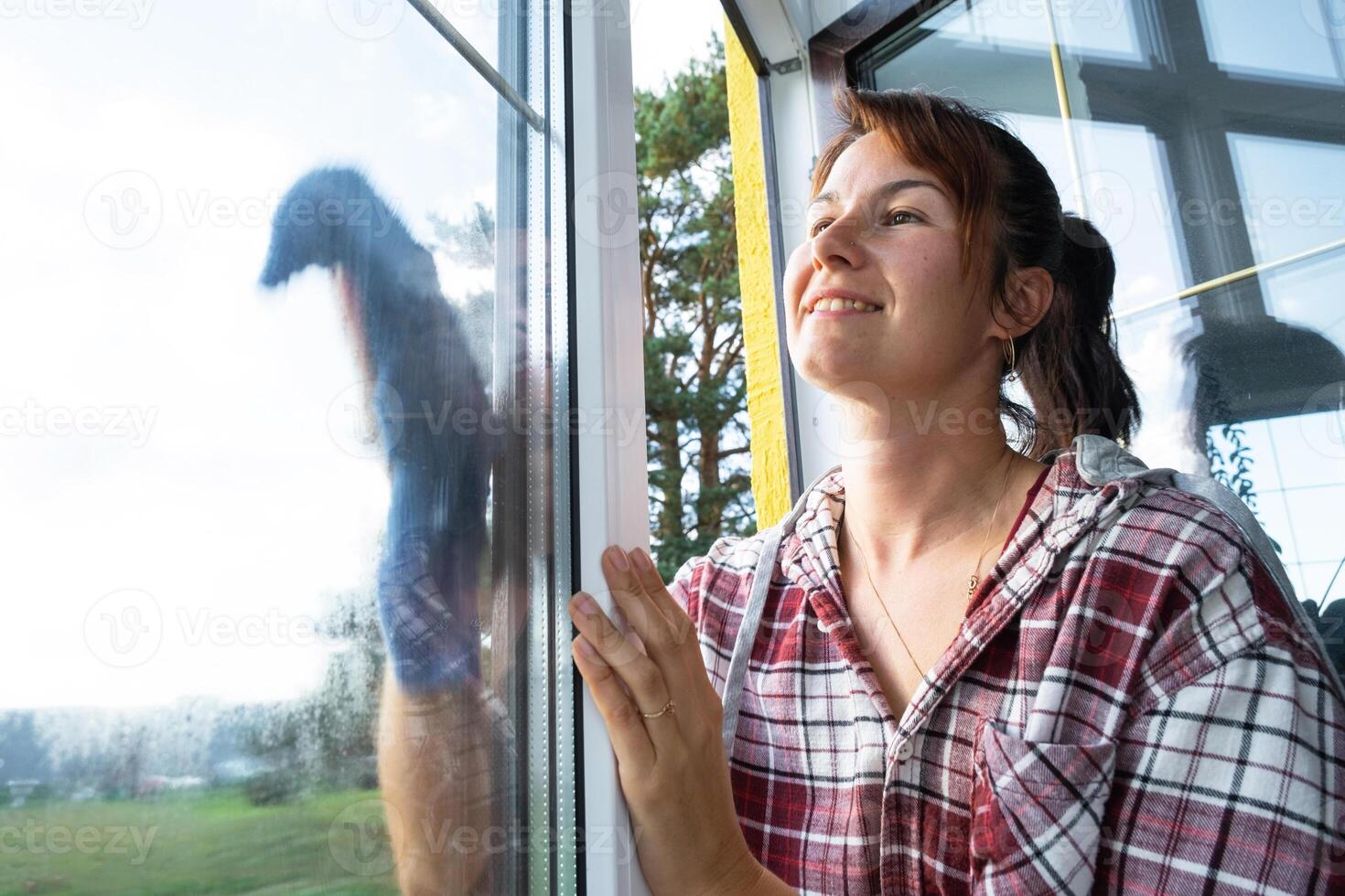 Woman manually washes the window of the house with a rag with spray cleaner and mop inside the interior with white curtains. Restoring order and cleanliness in the spring, cleaning servise photo