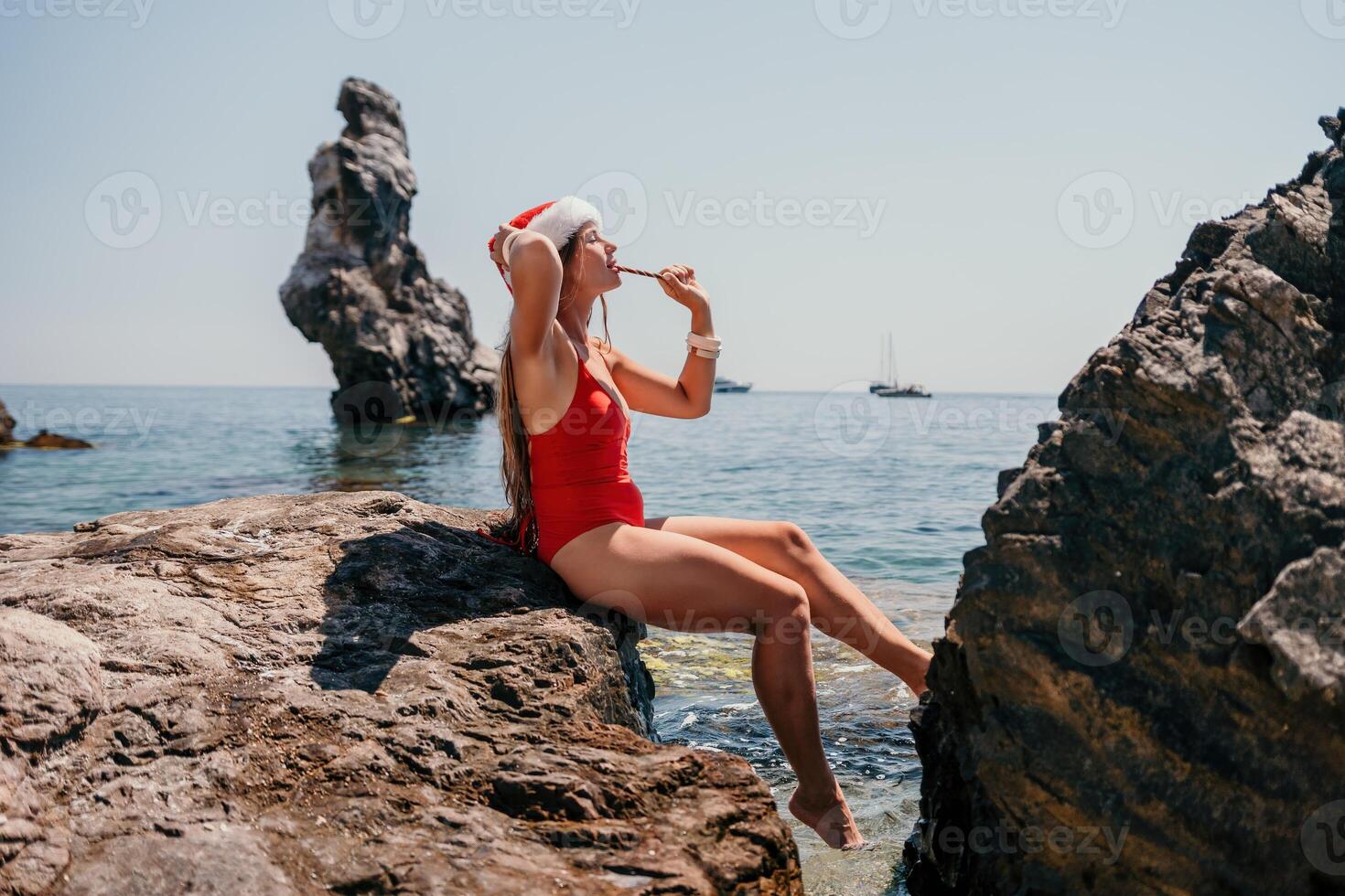 Woman travel sea. Happy tourist enjoy taking picture on the beach for memories. Woman traveler in Santa hat looks at camera on the sea bay, sharing travel adventure journey photo