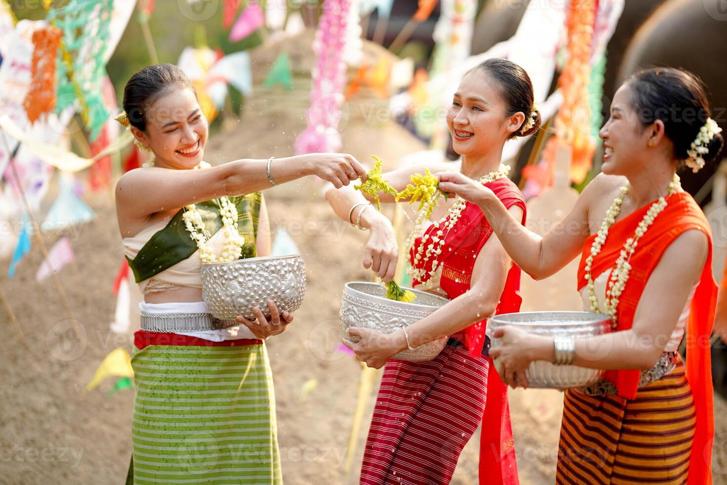 grupo de tailandés mujer mercancía tailandés tradicional vestir jugar a espolvorear agua en el tailandés nuevo años día o Songkran festival en un divertido camino en elefante y pila de arena antecedentes. foto