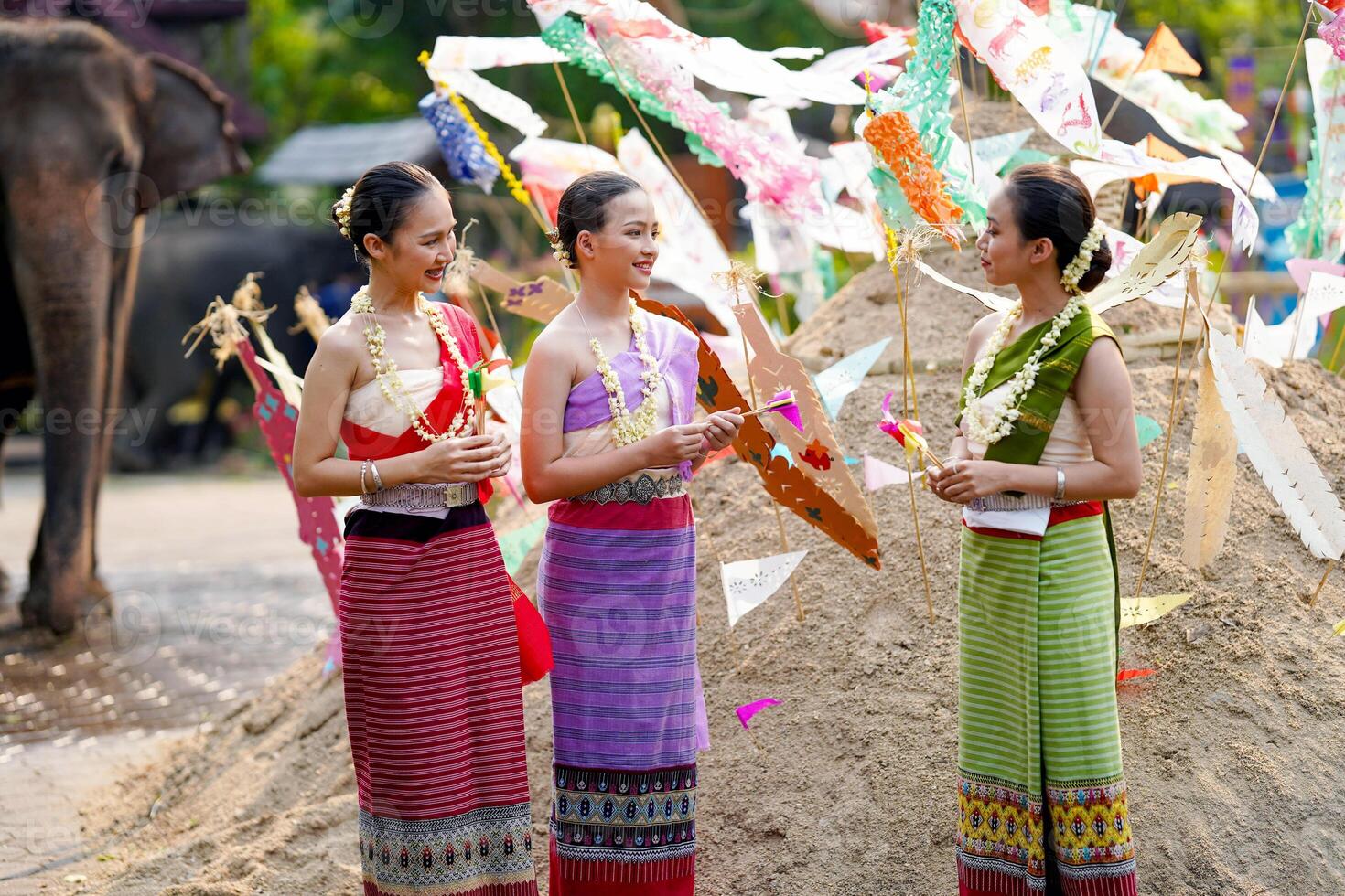 Beautiful Thai young lady ware Thai traditional dress stand and chatting on pile of sand in temple and blurred background. photo