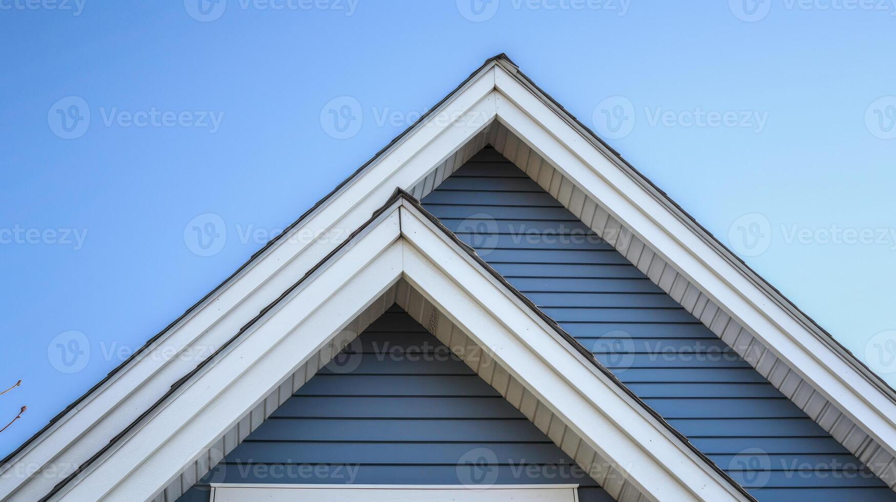 AI generated The top roof and gable on a blue house with white trim, against a blue sky background. photo