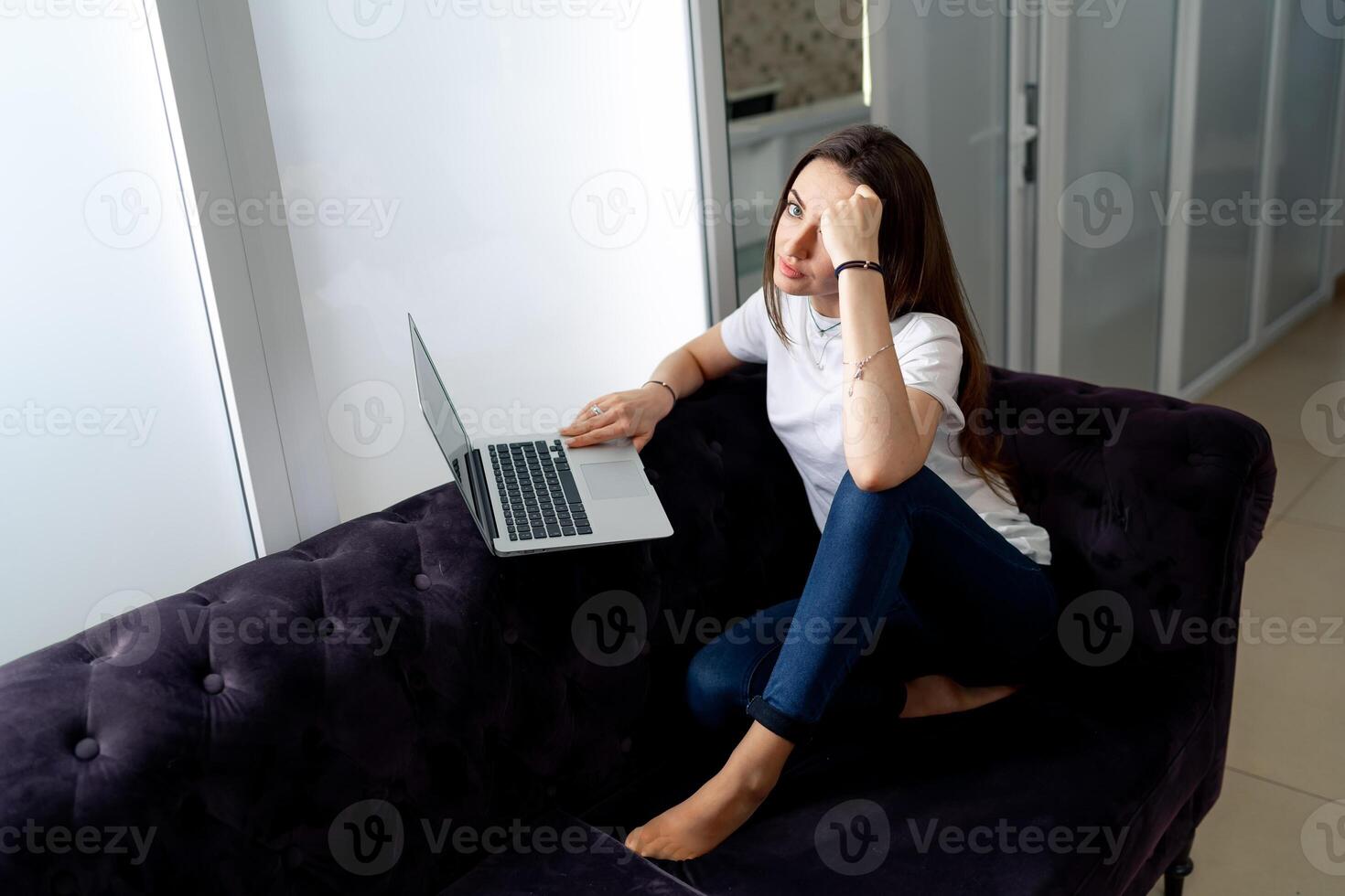 Close-up of ambitious girl working from home. Woman sit on sofa and using laptop with happy expression. photo