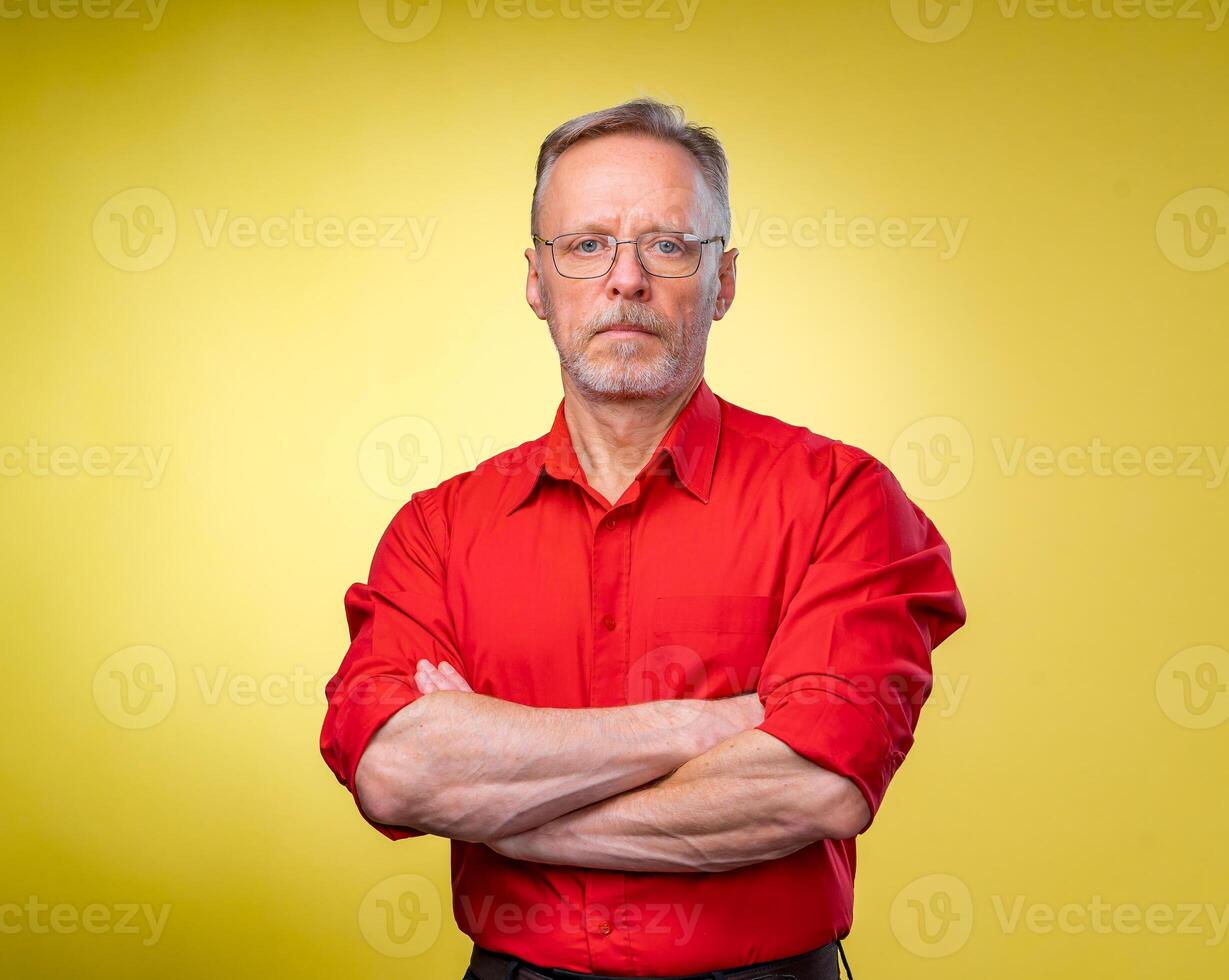 medio longitud imagen de un medio Envejecido negocio hombre sonriente con brazos cruzado. solado en un amarillo antecedentes foto