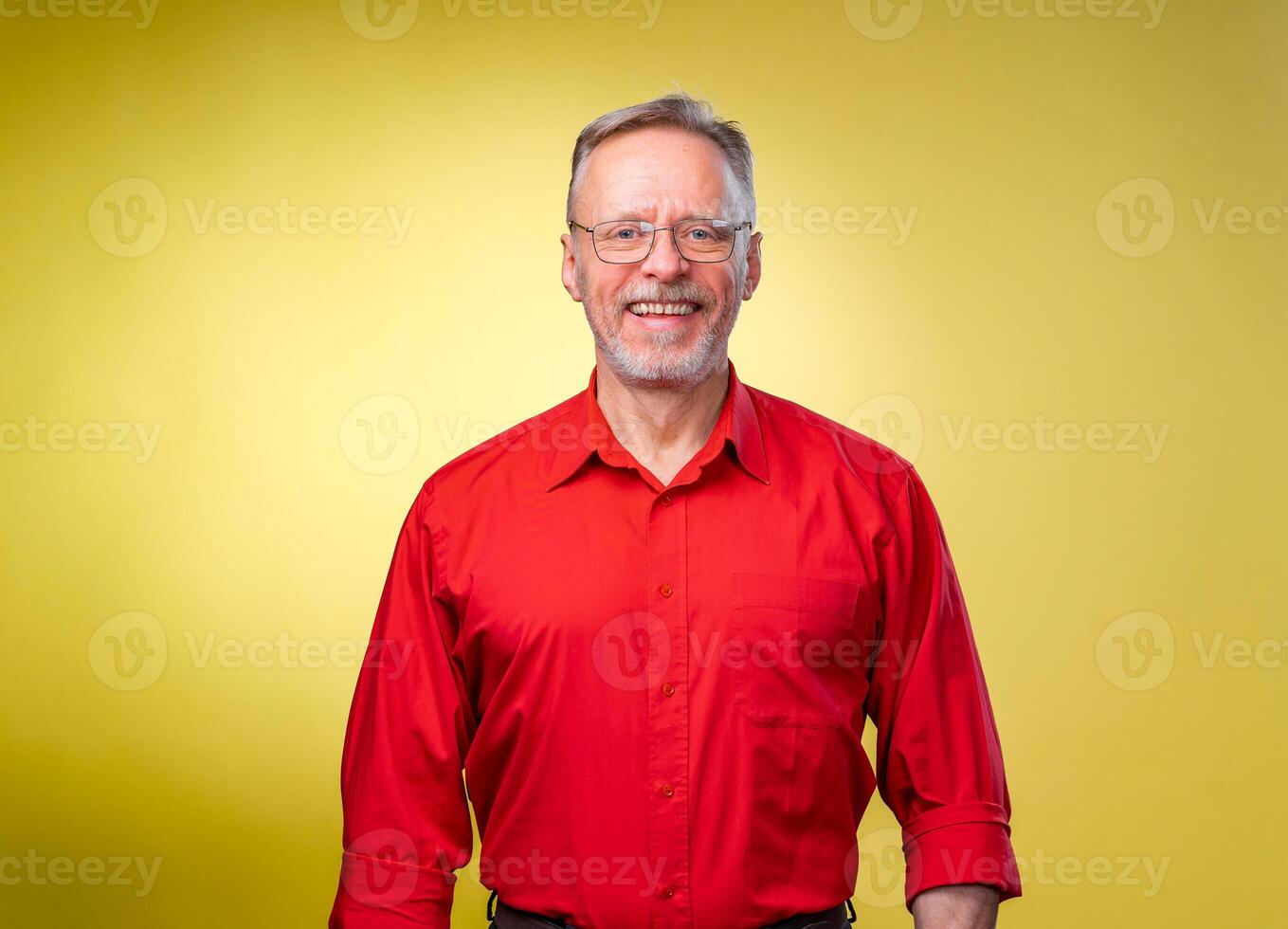 Confident middle aged man in red shirt with straight arms over yellow background photo