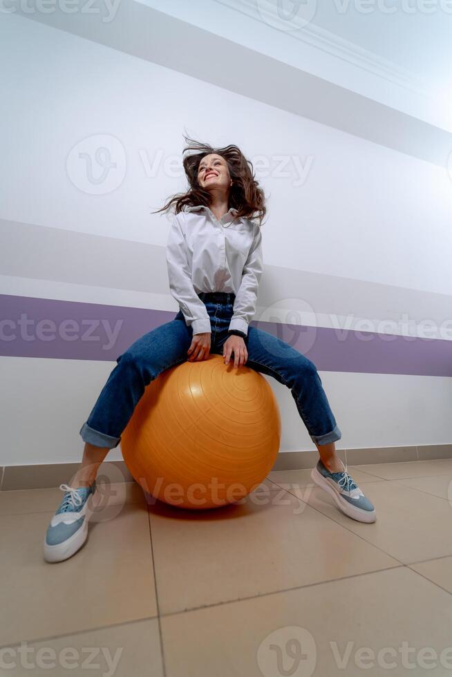 Woman sitting on fitness ball and jumping. Exercises for abs, legs and back. Healthy life style. photo