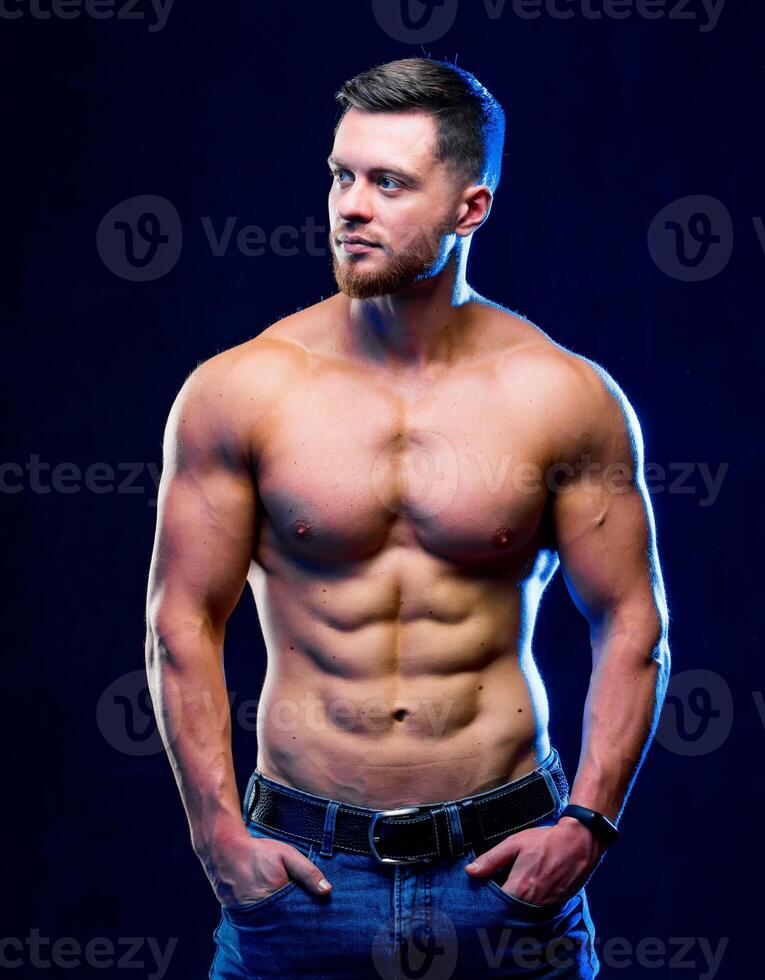 Closeup of a handsome power athletic man bodybuilder. Fitness muscular body on dark background. Closeup photo