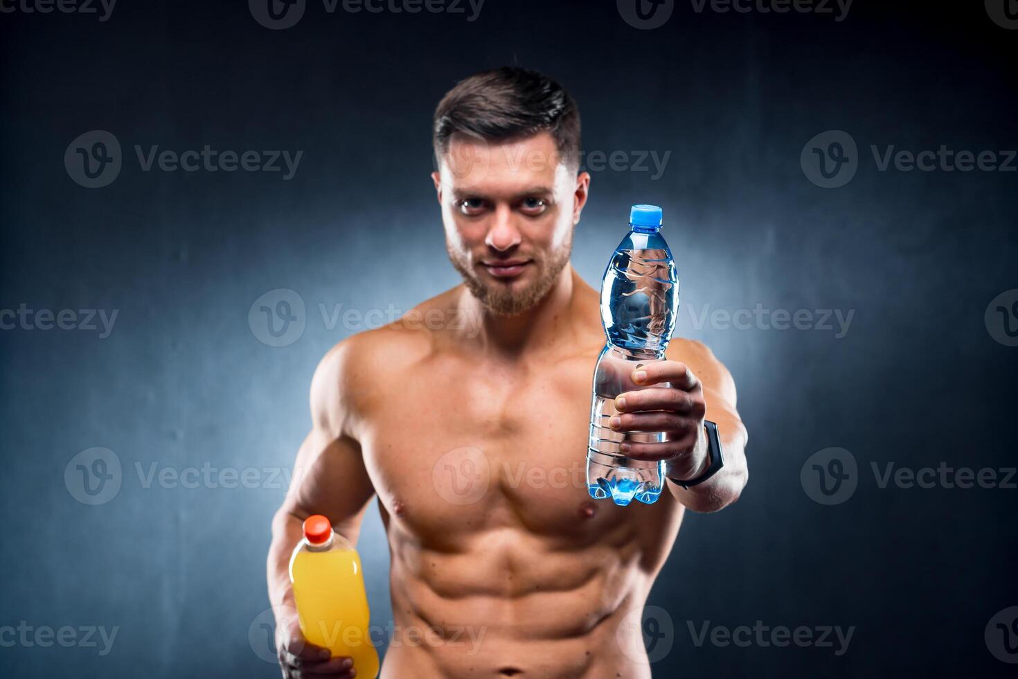 Sexy sportsman holding a bottle of water and soda. Choosing between healthy and harmful drink. Portrait. Closeup photo