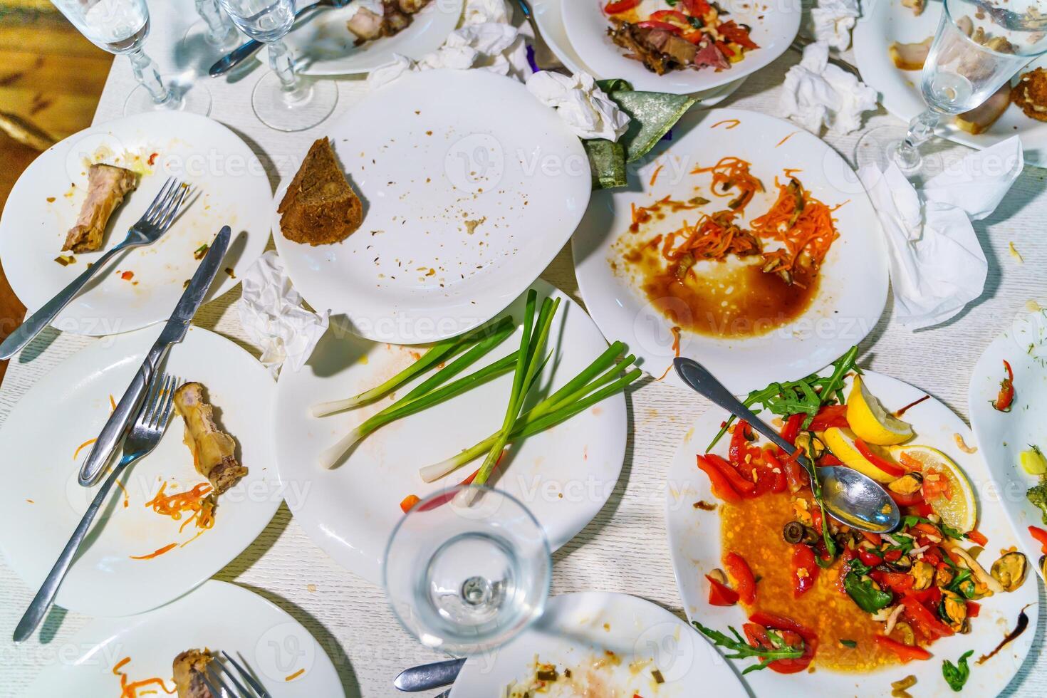 The leftover food and dirty dishes on the restaurant table. Scraps left over after the party. photo