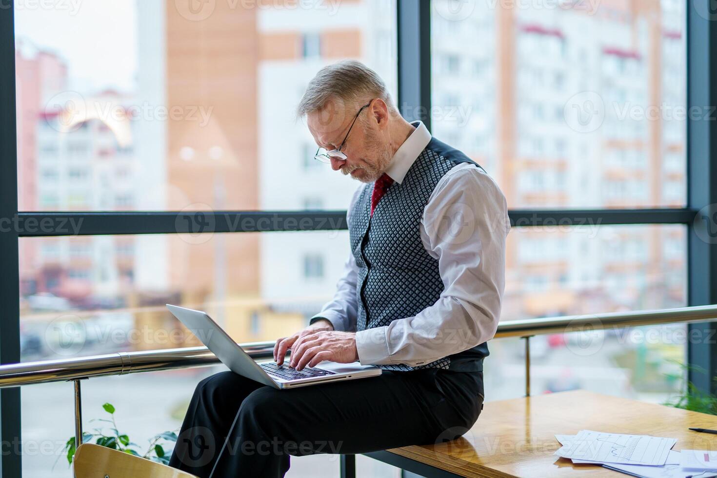 Side view on man with laptop on knees. Working manager. Neatly weared man in suit. photo