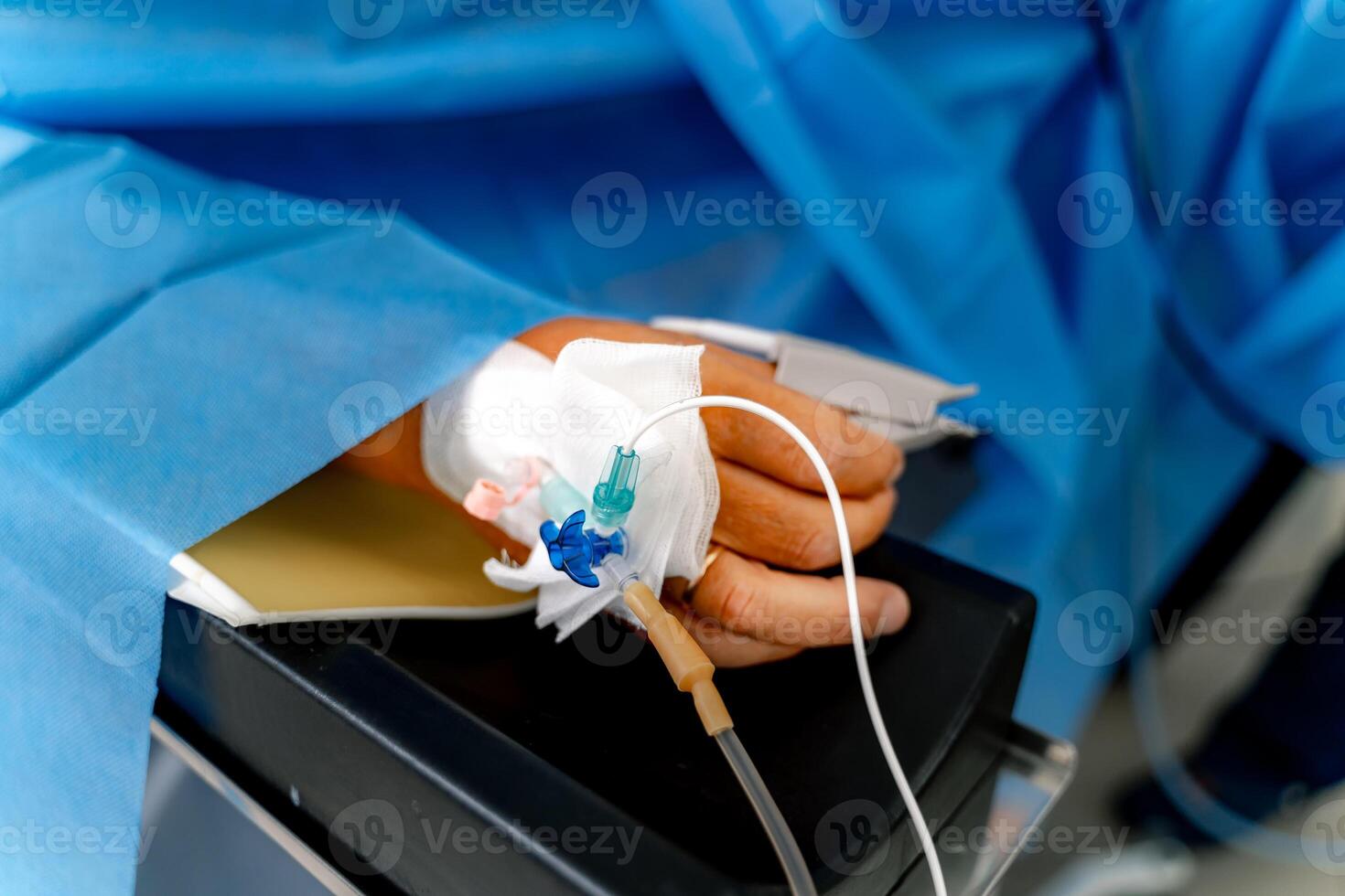 A catheter with a syringe in the hand of a patient lying on an operating table. The process of surgery under general anesthesia. Anesthesia is administered through a syringe. photo