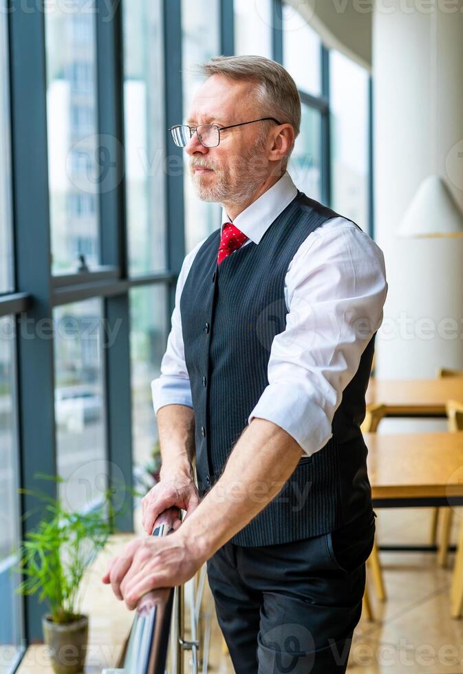 Man standing near window in modern room with high panoramic windows. photo