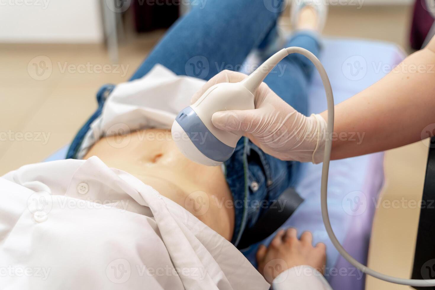 Pregnant woman getting ultrasound from doctor. Ultrasound equipment in clinic. Selective focus on belly. photo