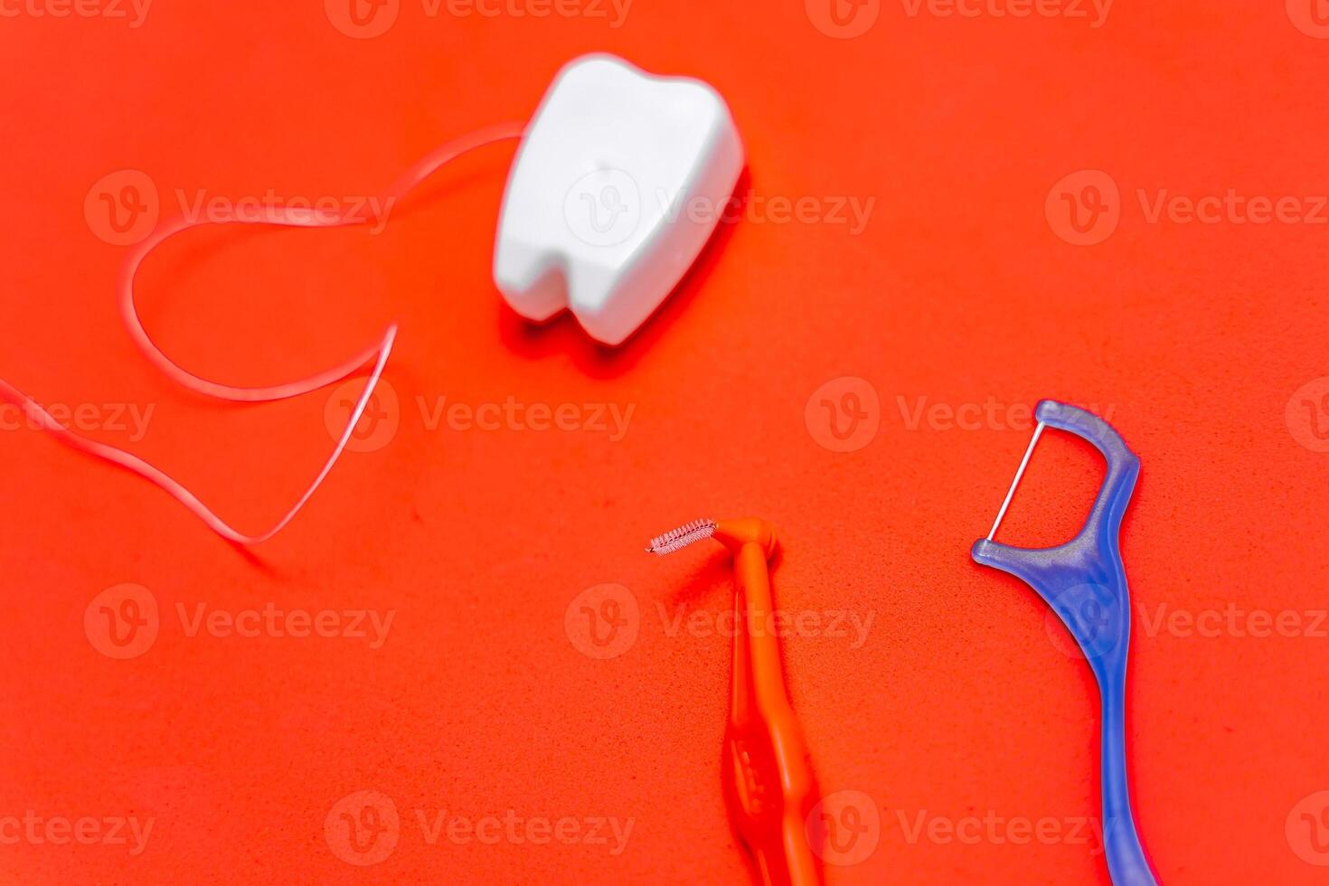 Different types of dental floss and tooth picks on red background. Dental floss in tooth toy shape. photo