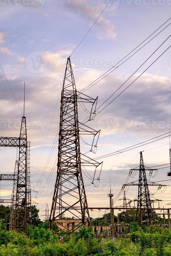 Electricity pylons and high-voltage power lines on the green grass. Power plant. Electrical power grid. View from below. photo