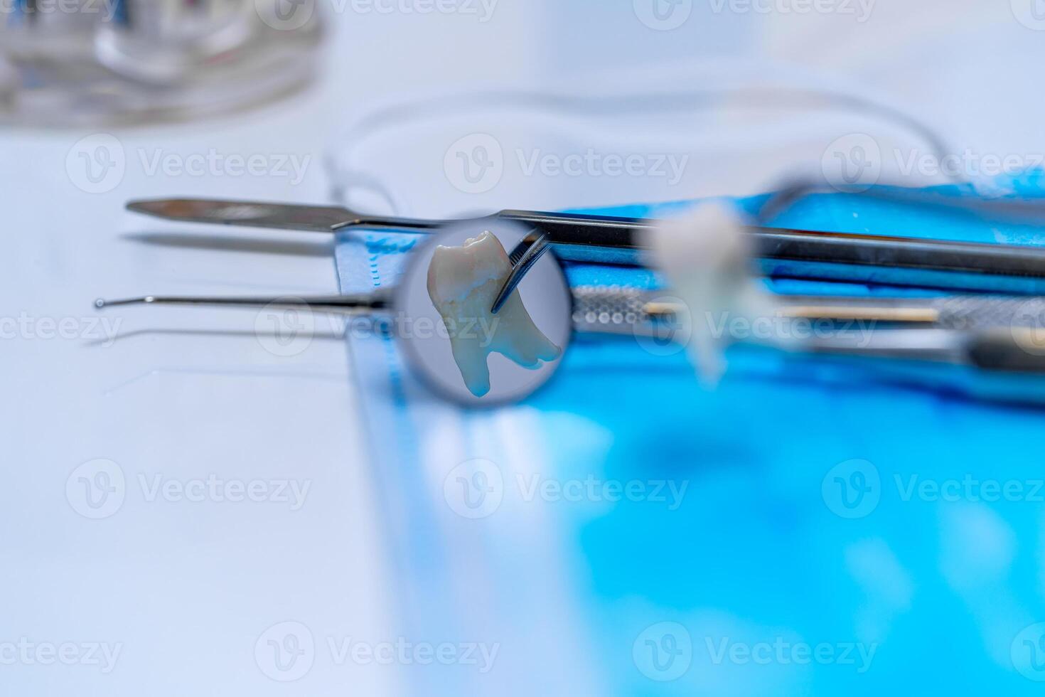 Metal dentist instruments over medical mask. White table background. Selective focus. photo