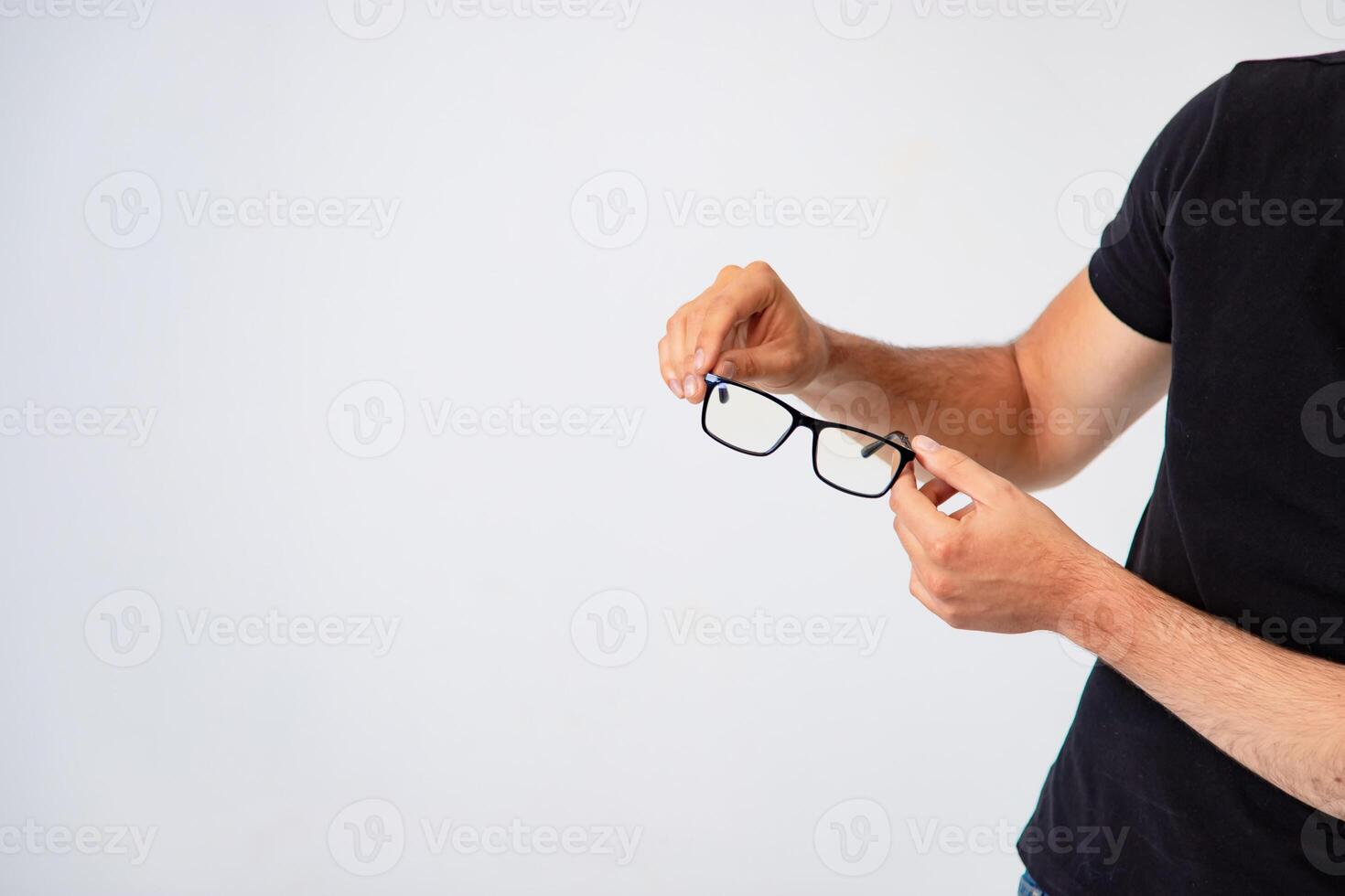 Man s hands holds trendy glasses with black rim on a white background in the studio. Close-up photo