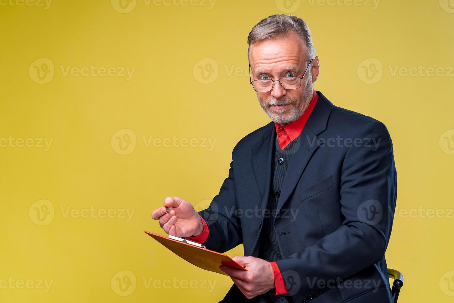 Middle aged manager holding folder and looking in front. Isolated on yellow background smiling to the camera. photo