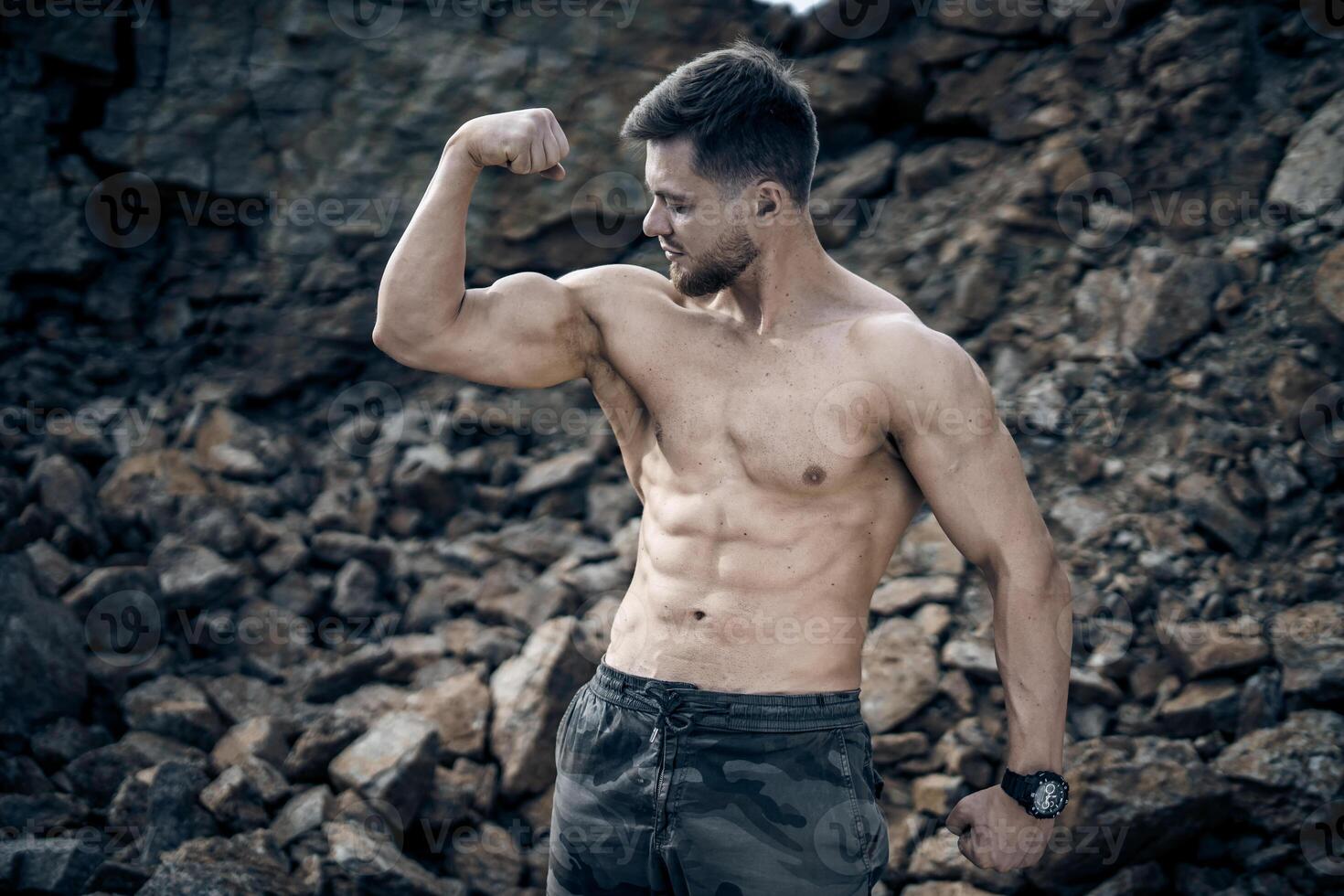 Young sporty man posing with perfect abs outdoor. Looking at the side. Shirtless muscular body. Closeup. photo