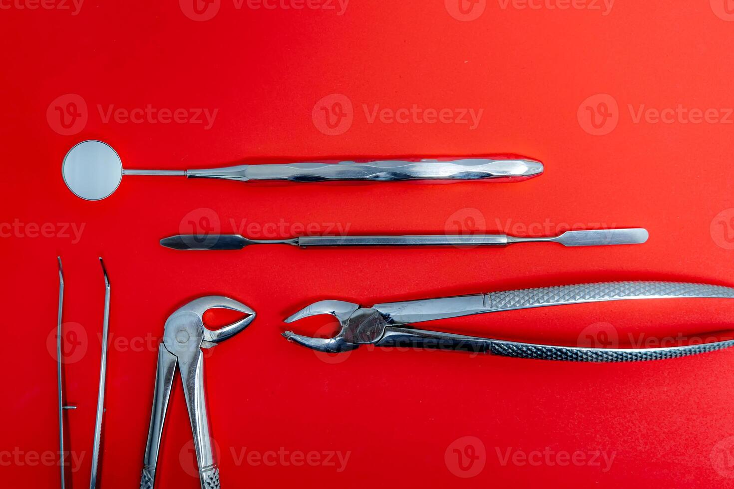 Art photo for dental concept. Set of metal dental instruments on red background.