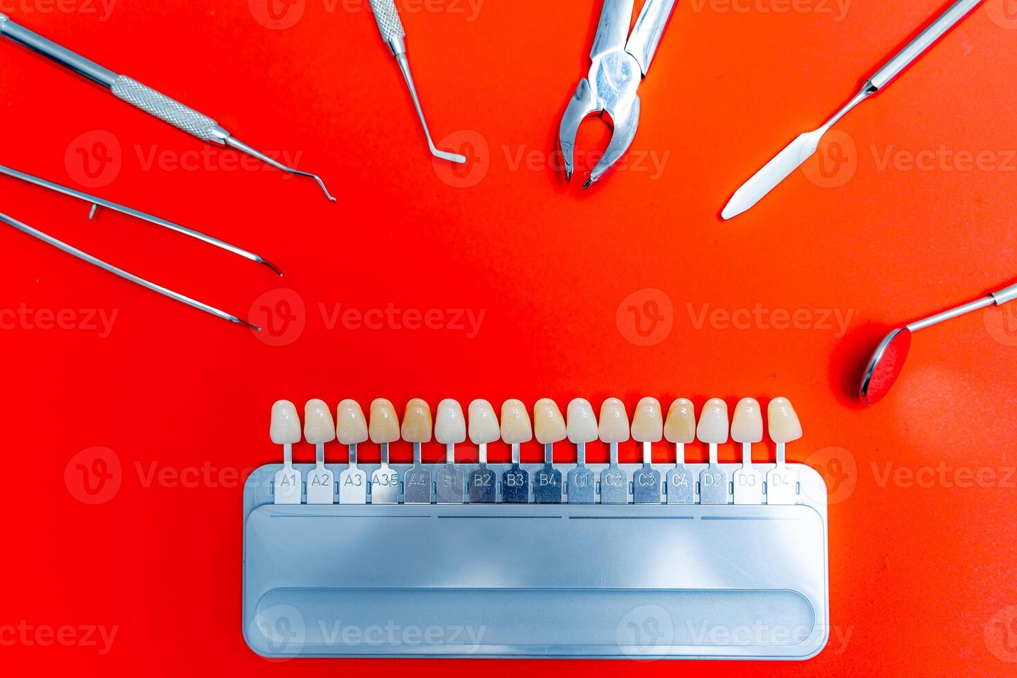 Color tone palette in the middle. Metal dental instruments around. Red background. photo