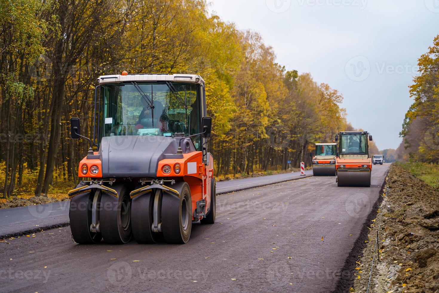 Road repair, compactor lays asphalt. Heavy special machines. Asphalt paver in operation. Heavy vibration roller at work paving asphalt, road repairing. Selective focus. Side view. Closeup. photo